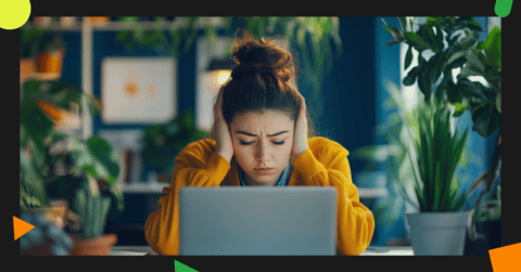 A person wearing a yellow sweater sits in front of a laptop, holding their head in distress, surrounded by green plants in a well-lit room. They seem overwhelmed by Facebook like & share competitions.