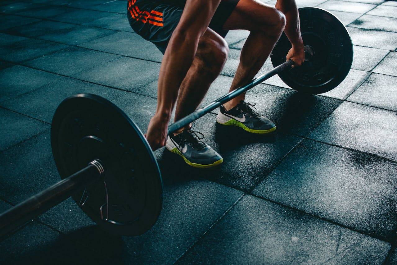 A man lifting a barbell in a gym.