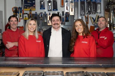 Four people standing in front of a counter in a shop.